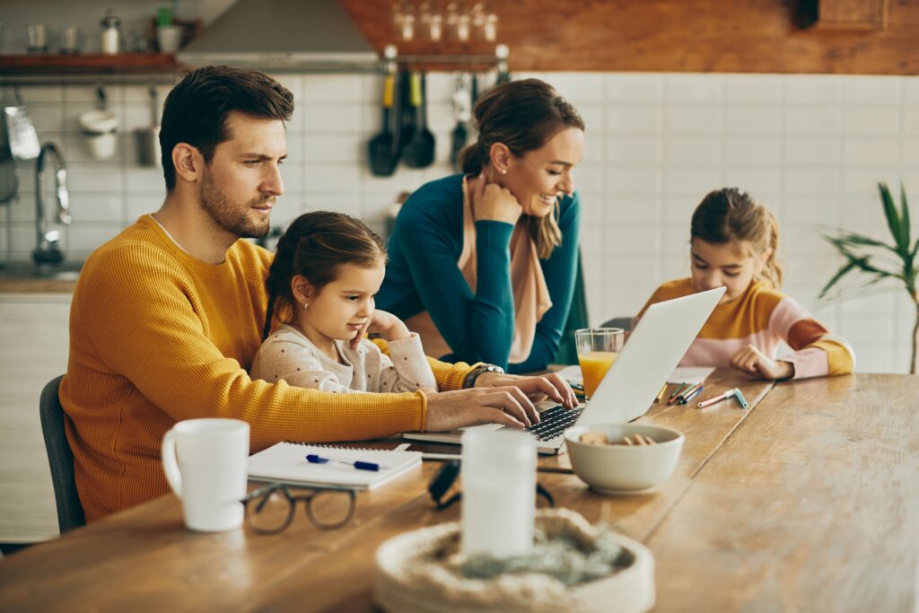 hombre-adulto-medio-que-trabaja-computadora-portatil-mientras-su-familia-casa